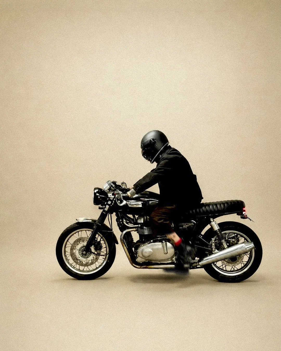 Lalo riding his Triumph cafe racer in the studio