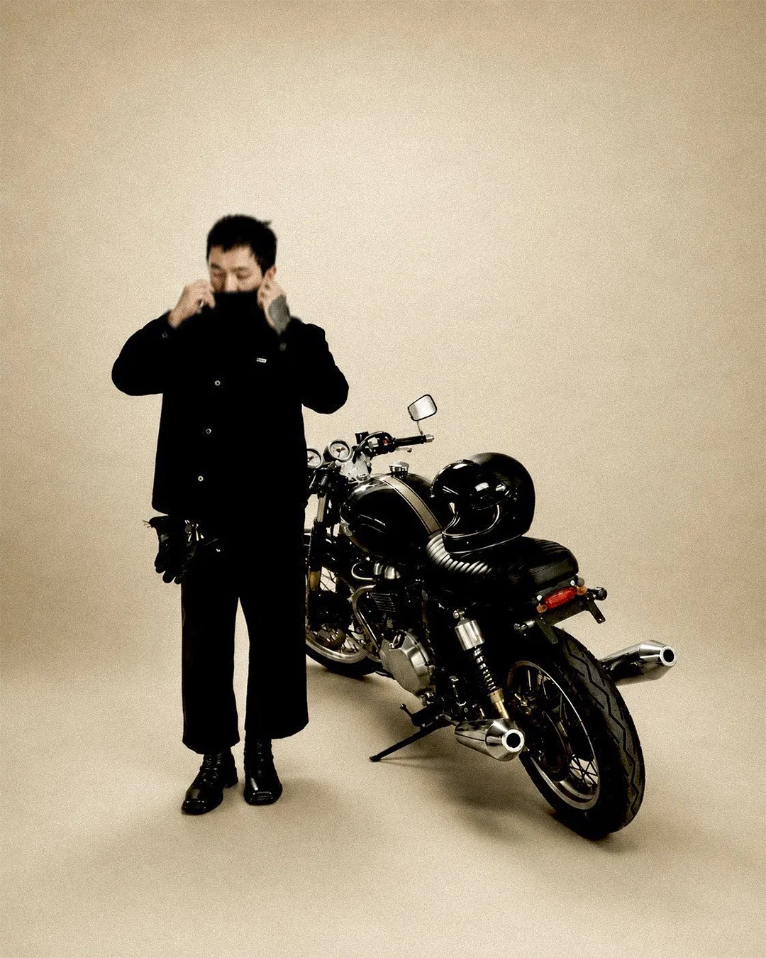 Lalo putting on his helmet next to a parked cafe racer