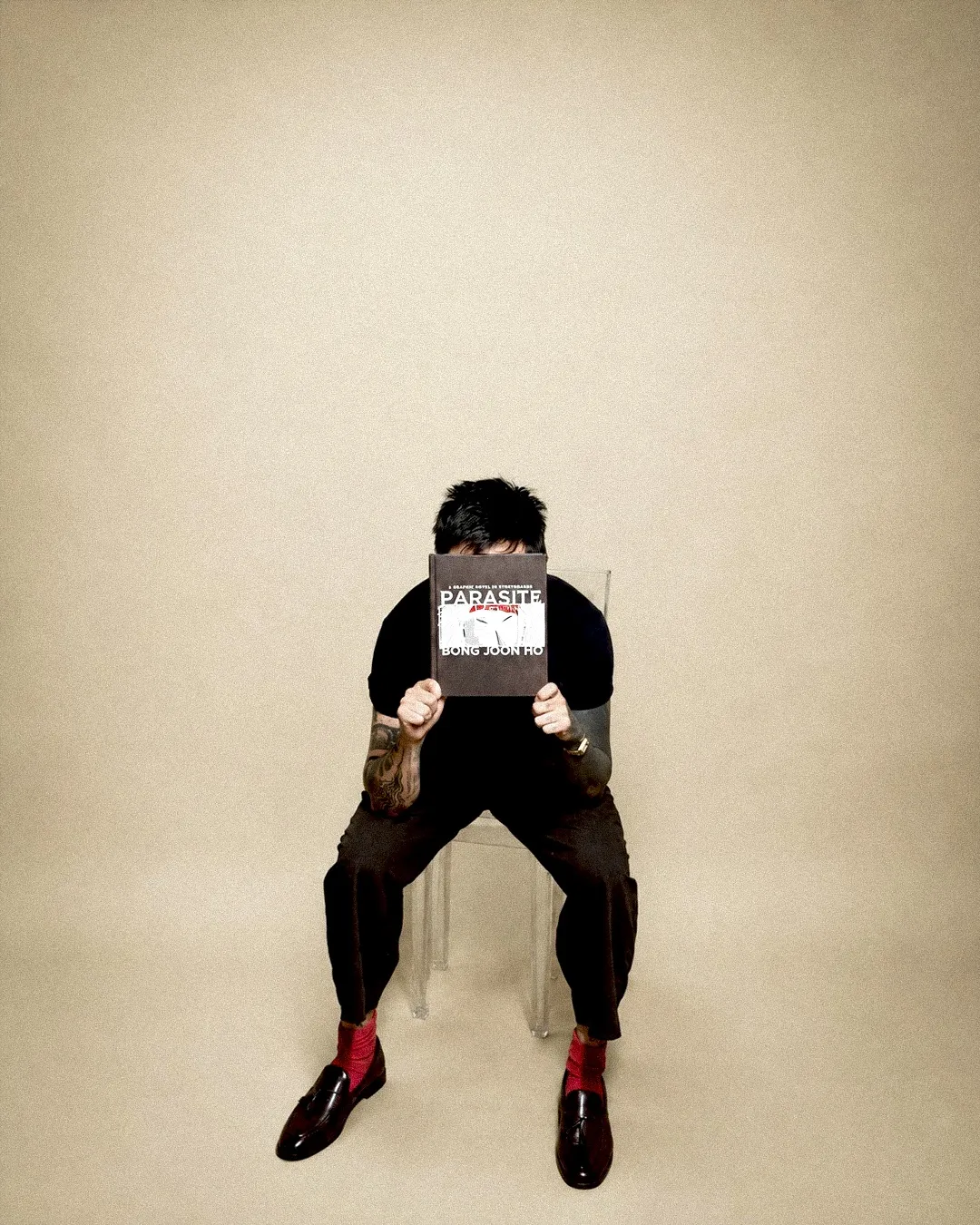 Lalo seated, reading the Parasite storyboard book by Bong Joon-ho