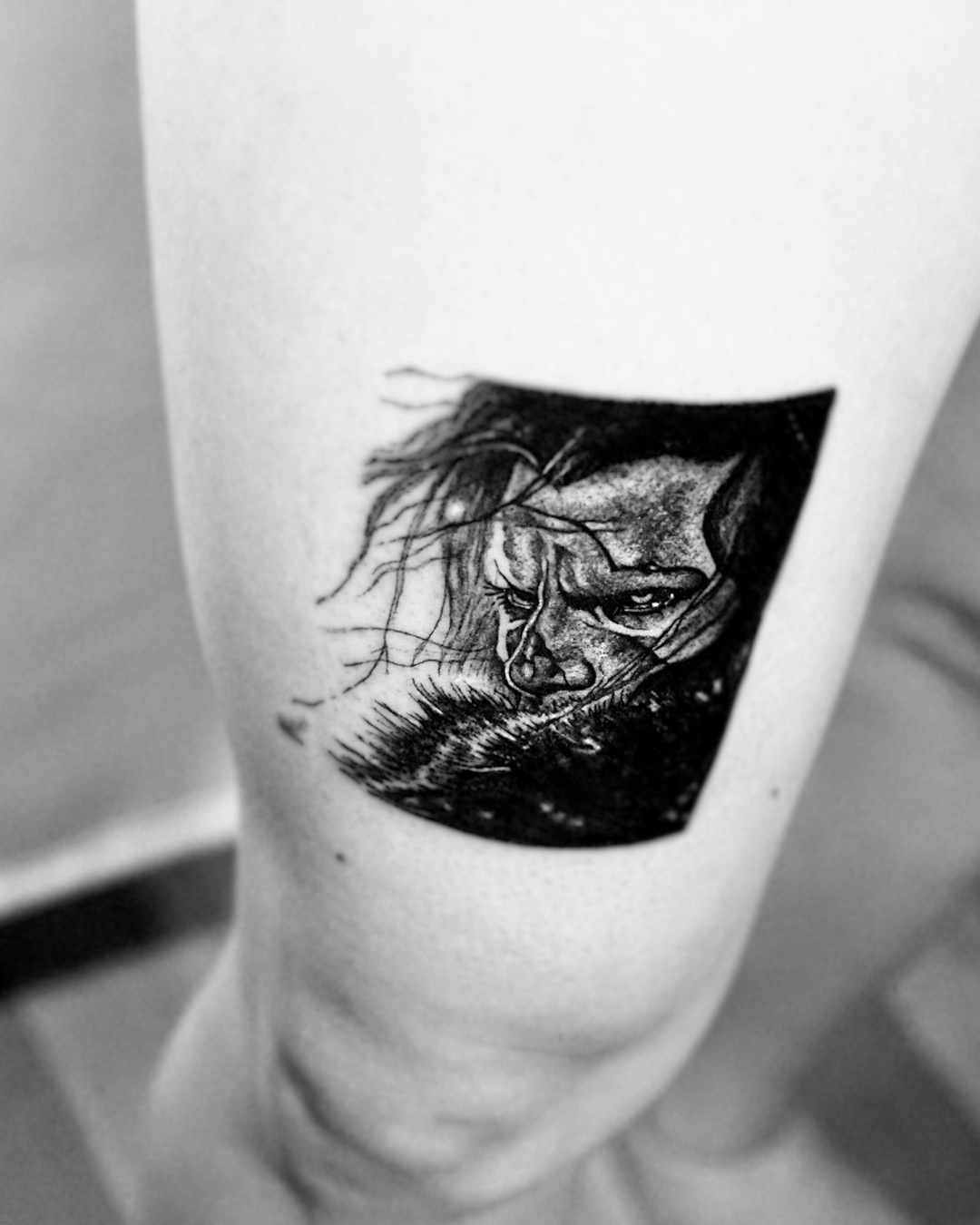Close-up of the Frank tattoo: framed black and grey portrait of a brooding hooded face with intense detail in the linework