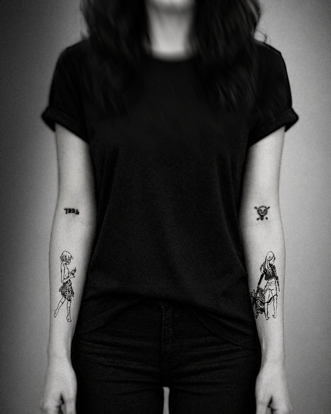 Sketch-style tattoos on both forearms photographed straight-on: a small wandering figure on the left, a girl with a skull-and-crossbones on the right